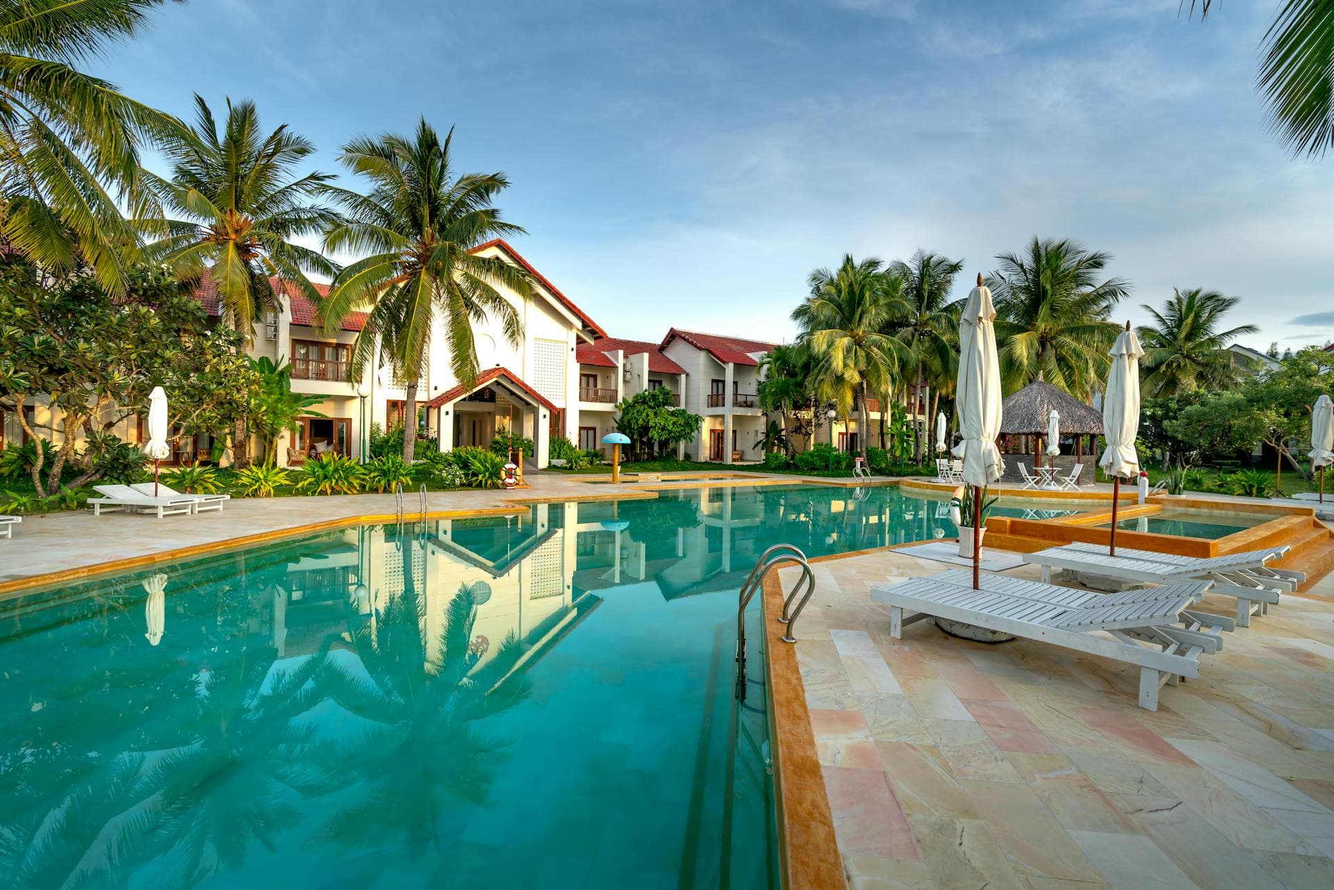 A luxurious resort pool framed by palm trees beside a tropical lagoon